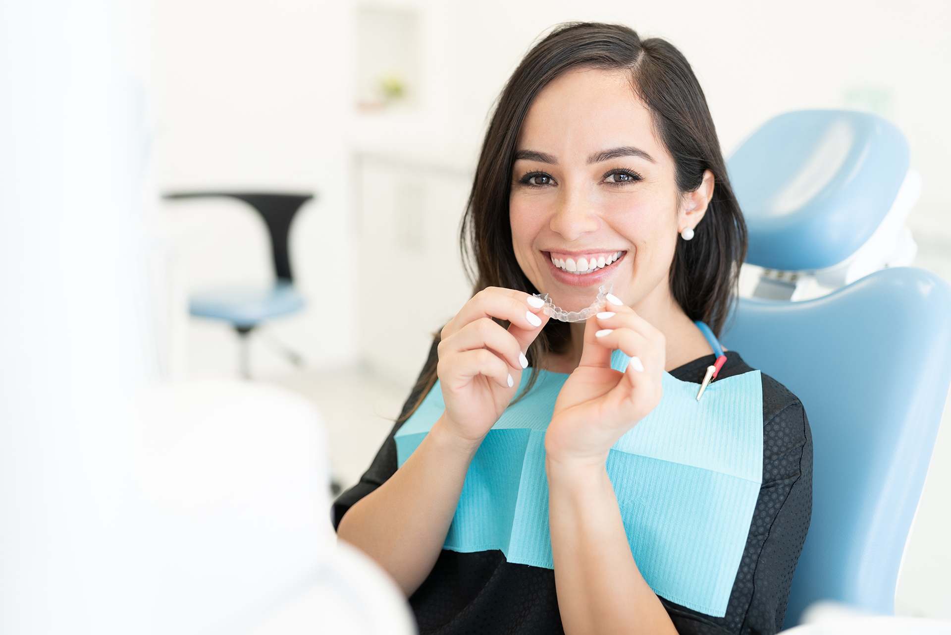Woman sitting at dental chair with smiling expression, holding toothpicks.