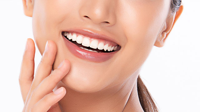 The image displays a close-up of a smiling woman with her hand on her chin, showcasing her teeth and lipstick, against a white background.