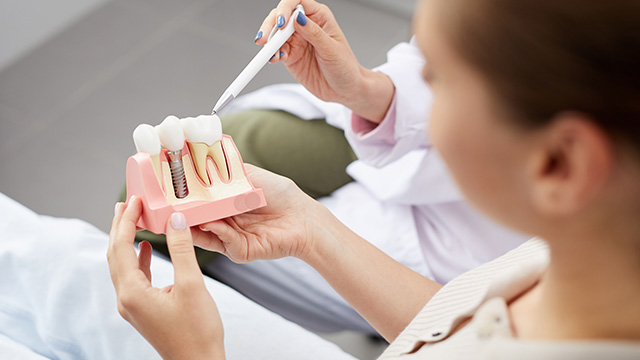The image depicts a dental professional examining teeth using a magnifying glass.