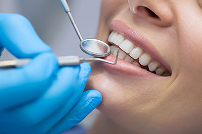 A dental hygienist cleaning a patient s teeth with a toothbrush, set against a blurred background.