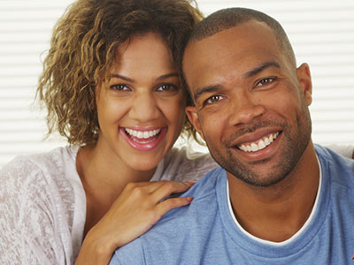 The image shows a man and a woman posing for a photo with smiles on their faces  they appear to be happy and are embracing each other.