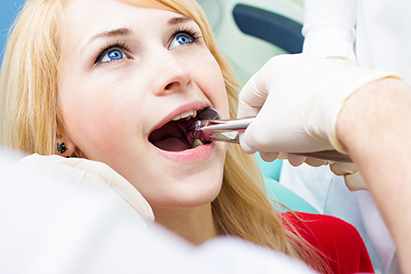 A woman receiving dental care with a dentist working on her teeth.