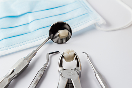 The image shows a collection of dental tools, including scissors, tweezers, and a toothbrush, with a focus on a dental implant being placed into a prepared socket using a drill.