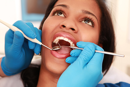A woman receiving dental treatment with a dental hygienist performing the procedure.