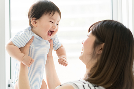A woman holding a baby who appears to be smiling, with both looking upwards.