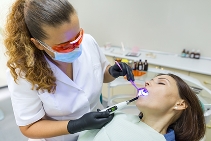 A dental hygienist performing oral care on a patient using an electric toothbrush.