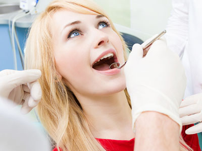 A woman receiving dental care with a dentist performing the procedure.
