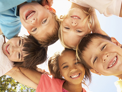 The image depicts a group of children posing for a circular photo with big smiles on their faces.
